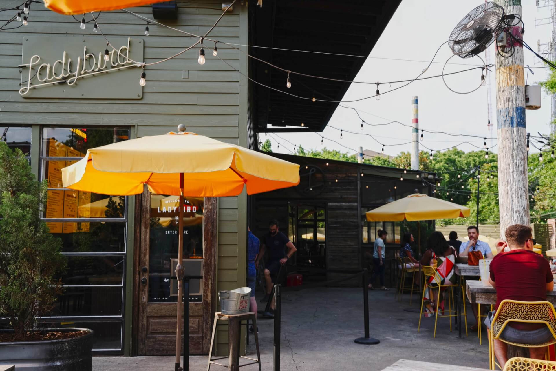 Outdoor patio at Ladybird with string lights, umbrellas, & diners